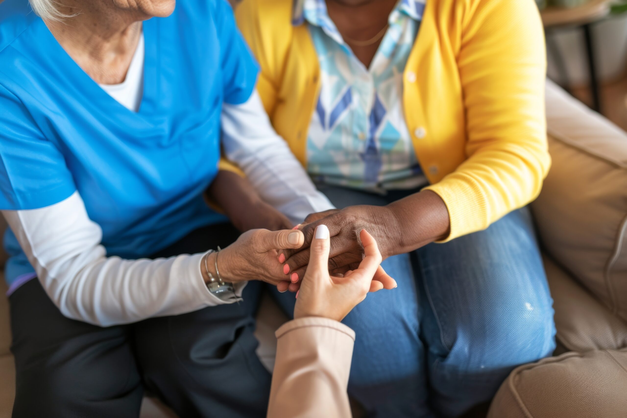 A woman in a blue scrubs is holding a woman’s hand